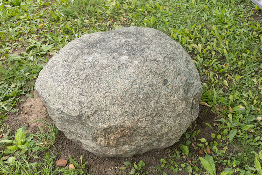 Large round granite boulder on green grass field.