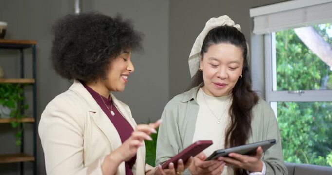 Diverse female coworkers in blazers tapping phone and comparing tablet at office to align content