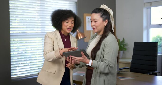 Female team in workwear showing tablet at desk after left prompt, explaining while right holding