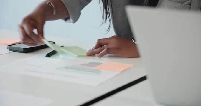 African American woman in light shirt reviewing chart and writing green notes for meeting at table