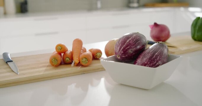 Camera is panning right and forward, revealing carrots with knife on white counter for display