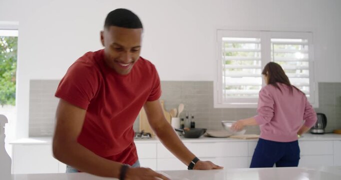 African American couple cleaning with man wiping kitchen island with rag as woman drying dishes