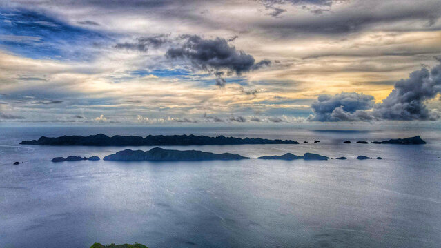 Aerial view of Raja Ampat Regency islands surrounded by the vast ocean under a dramatic cloudy sky in Southwest Papua, Indonesia.