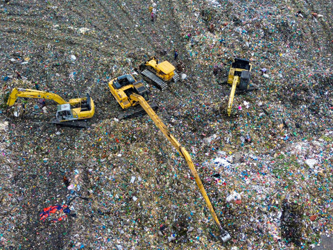 Aerial view of Amin Bazar Waste Disposal Area with heavy excavators working on a massive pile of waste and workers sorting through debris in Bongaon Union, Dhaka Division, Bangladesh.