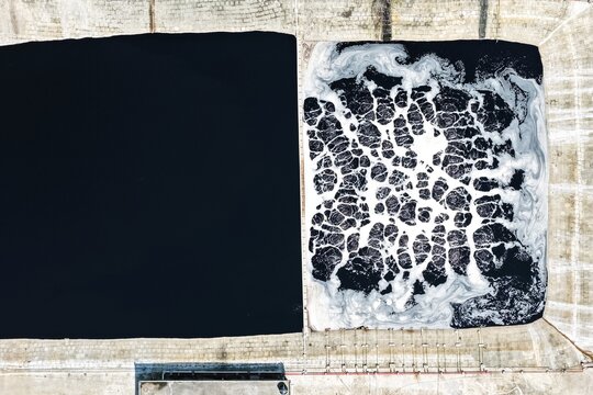 Aerial view of Aminbazar Landfill showing two treatment ponds, one with dark water and the other with white foam patterns, in Aminbazar, Dhaka Division, Bangladesh.
