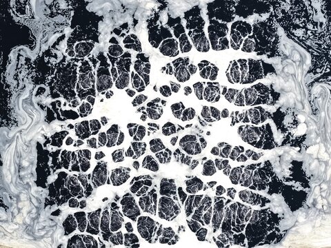 Aerial view of the Aminbazar Landfill showing thick white foam patterns on dark polluted water in Aminbazar, Dhaka Division, Bangladesh.