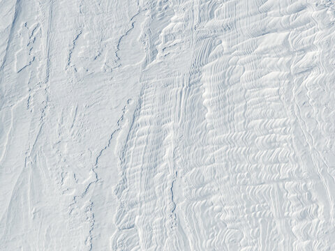 Aerial view of wind-swept snow patterns and textured drifts covering the arctic landscape in Valldal, More og Romsdal, Norway.
