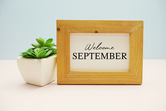wooden frame with text "WELCOME SEPTEMBER" and small artificial plant