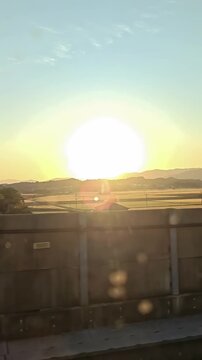 Sunset from shinkansen high speed train passenger POV passing japanese rural city, track, Rural Travel Journey, Train Railway Transportation
