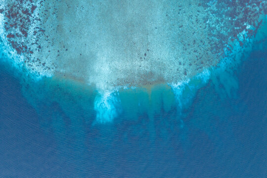 Aerial view of the river mouth where sediment-rich water meets the deep blue sea, showing clear patterns of water flow and coastal textures in Valldal, More og Romsdal, Norway.