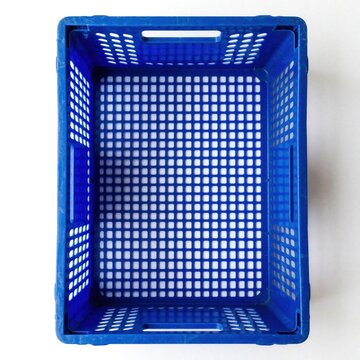 Top view of empty blue plastic crate with handles. Rectangular perforated container for storage, transport. Versatile utility basket used in warehouse, grocery market, logistics. Simple bright blue