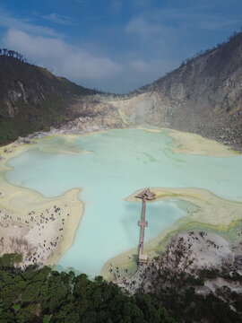 Aerial view of Kawah Putih Ciwidey crater lake with its turquoise water, wooden pier, and surrounding volcanic landscape in Bandung, West Java, Indonesia.