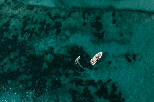 Aerial view of a yacht and a small boat cruising through the turquoise waters of Formentera, Balearic Islands, Spain.