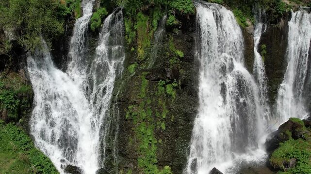 Aerial view of multiple cascades of Shaki Waterfall over green rocks