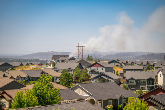 A wildfire plume of smoke rises in the hills above Spokane, Washington State, viewed from a hillside subdivision in the Spokane Valley area.