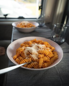 Cooked fusilli with tomato sauce and parmesan cheese on the table in the campervan, Tinglev, Denmark