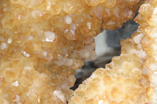 A close-up of a yellow geode of citrine. Mineral, crystal and gemstone and geology. Citrine druse and raw stone. Yellow background with minerals and crystal points. Geogical formation.