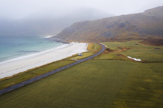 Drone shot, Fine sand beach with turquoise water, camping van in the distance, Haukland beach, Lofoten, Norway