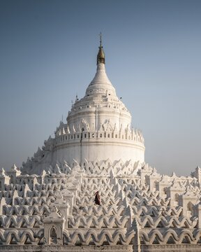 Buddhist monk stands with red umbrella in front of Hsinbyume Pagoda, Mingun, Myanmar