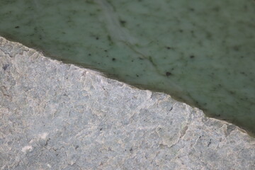 Close-up of a nephrite jade from Quebec. Green stone background and jade. Raw and polished jade. Geology science and mineral from Quebec. © Martine