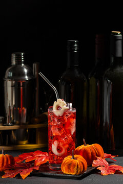 Spooky Halloween cocktail with eyeball garnish and mini pumpkins festive decoration and bar tools background