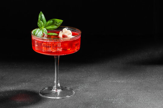 Elegant Red Cocktail Garnished With Fresh Basil And Flower Petal On Dark Background