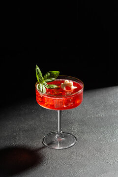 Halloween themed red cocktail with basil garnish and spooky ice cube on dark background ready for celebrations
