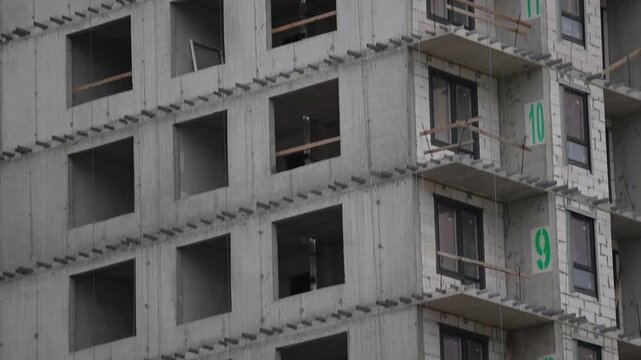 Multi story building under construction with exposed concrete structure and open window spaces, showing high rise development, construction progress and modern urban growth