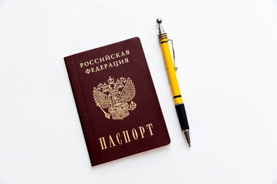 Russian Federation passport with gold emblem and text alongside a yellow and black pen on a white background. Official documentation and writing instruments concept