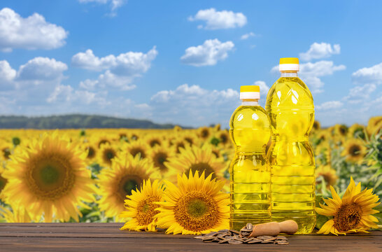 Sunflower oil bottles standing on wooden table with field