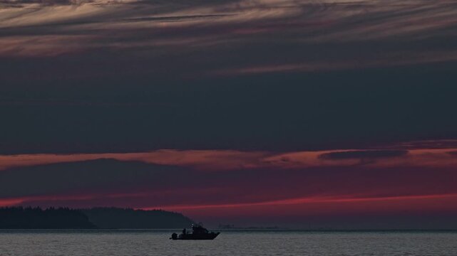 Cinematic 4K Sunset on calm water with silhouetted fishing boat