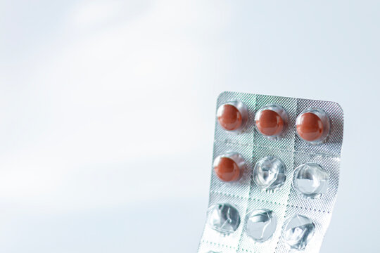 Silver blister pack of brown prescription medication pills with empty foil slots against a white background