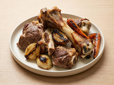 Roasted beef marrow bones with charred onions and carrots on a plate