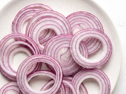 Sliced purple red onion rings arranged on a ceramic plate
