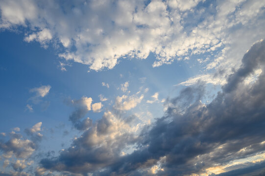 Clouds dance gracefully across a vibrant sky as the sun begins to set, painting a breathtaking canvas of colors