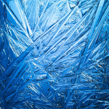 Ice frozen in intricate patterns of delicate crystals with brilliant contrasts of deep blues. Real unique patterned crystal formations. Sparkling window frost or icy cold winter frosting background.