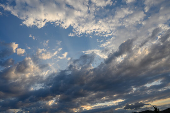 Dramatic clouds dance in the sky, painting a stunning backdrop as sunlight breaks through in the early evening