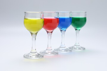 Fototapeta premium Colorful drinks in glasses on light grey background, closeup
