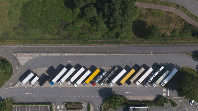 Portugal - 16 August 2026: Aerial view of a row of parked semi-trucks and trailers in a paved parking lot, seen from directly above.