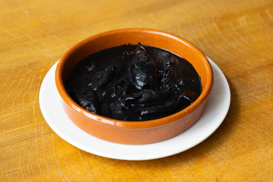Traditional squid in ink sauce served in rustic ceramic dish