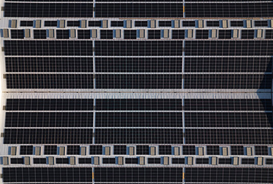 Portugal - 14 August 2026: Aerial view of solar panels installed on large industrial factory rooftops, showcasing decentralized energy production and sustainable infrastructure in Portugal.