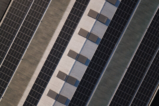 Portugal - 14 August 2026: Aerial view of solar panels installed on industrial factory rooftops, showcasing decentralized energy production.