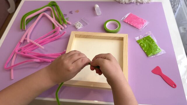 Young student creating a beautiful botanical artwork using fuzzy craft sticks and green decorative tape during an art therapy session or preschool masterclass animation