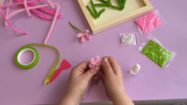 Whimsical kindergarten activity showing a little student making a colorful bouquet from fuzzy pipe cleaners to train precision and motor skills under tech trend