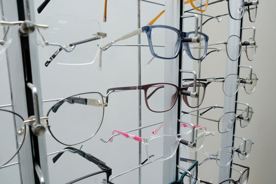 Modern eyeglass frames displayed on an optical store rack, showcasing a variety of stylish eyewear designs and colors.