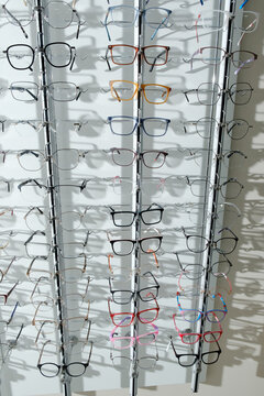 Modern eyeglass frames displayed on an optical store rack, showcasing a variety of stylish eyewear designs and colors.