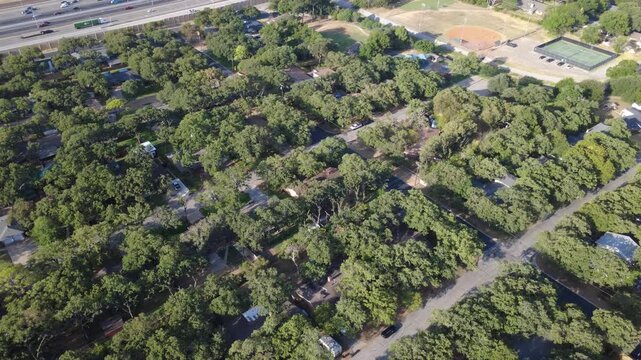 Lush residential tree canopy borders busy highway transit infrastructure along Airport Freeway. Detached ranch houses, green sports grounds, quiet residential lanes reflect local life, Hurst, TX