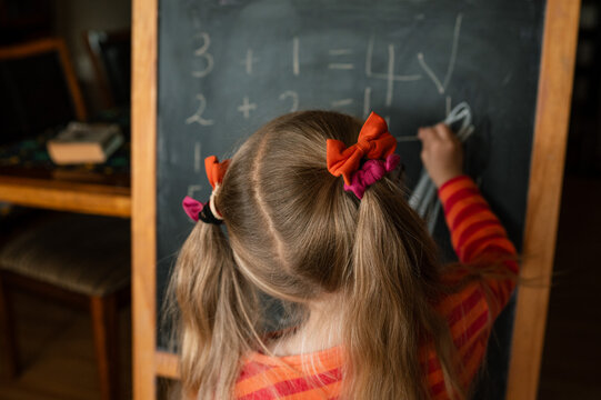 Little girl playing school on a black board at home