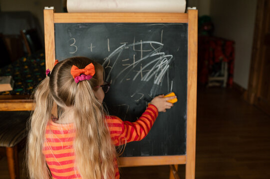 Little girl playing school on a black board at home