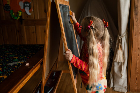 Little girl playing school on a black board at home